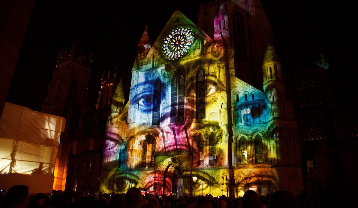 3D projection mapping execution - multi-color visuals of faces projected on an old building